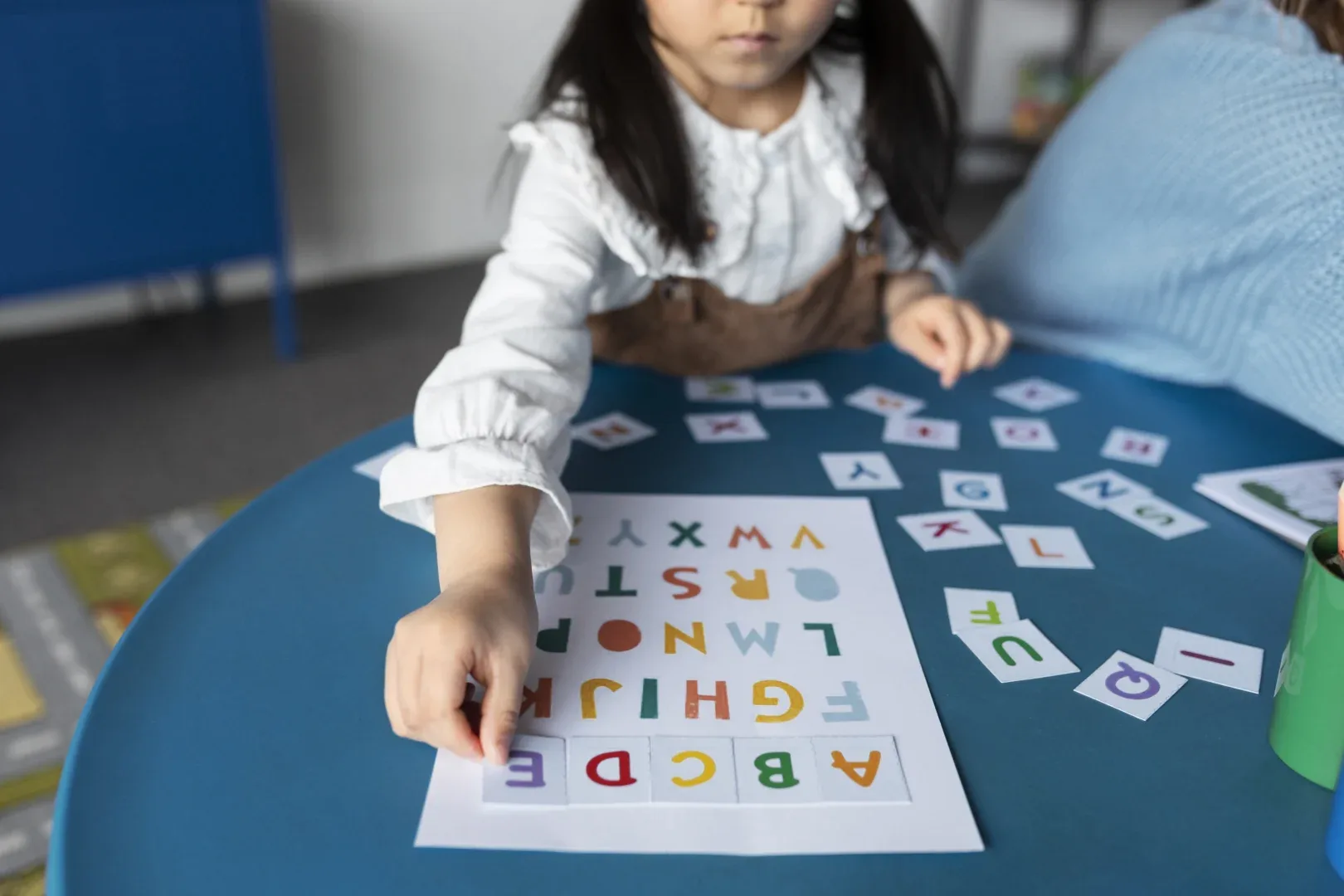 Pós EaD em Alfabetização: quais são as opções? | Foto de criança completando o abecedário com letras coloridas | FAVENI