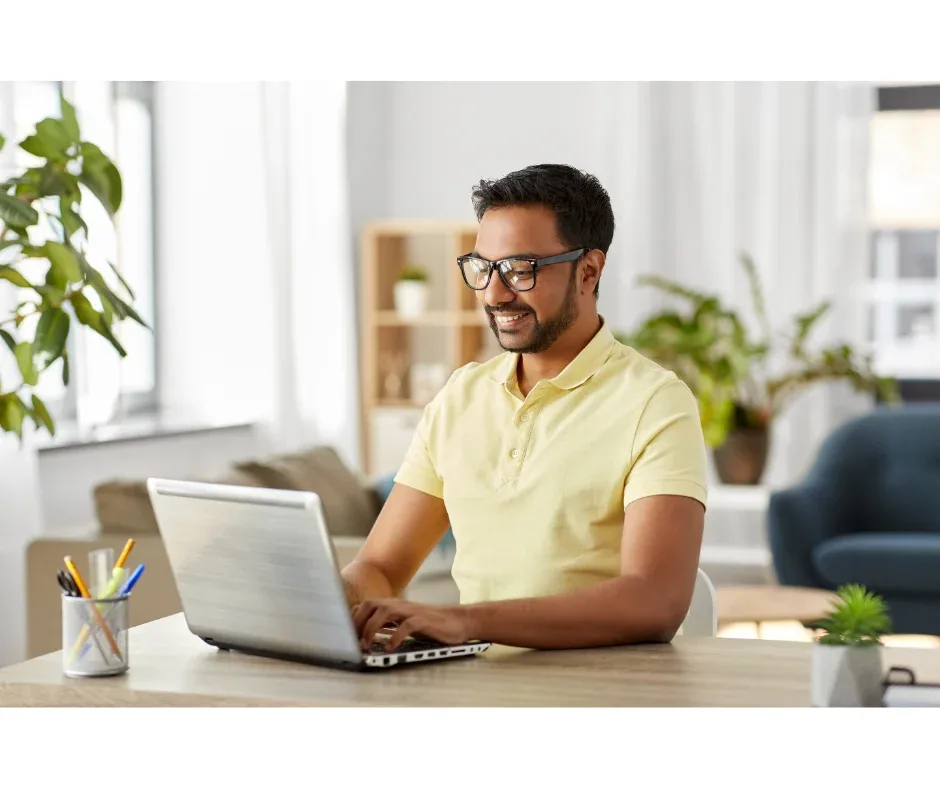 Me formei, e agora? Saiba o que fazer depois da faculdade!  | Foto de homem indiano com expressão feliz enquanto usa o notebook | FAVENI