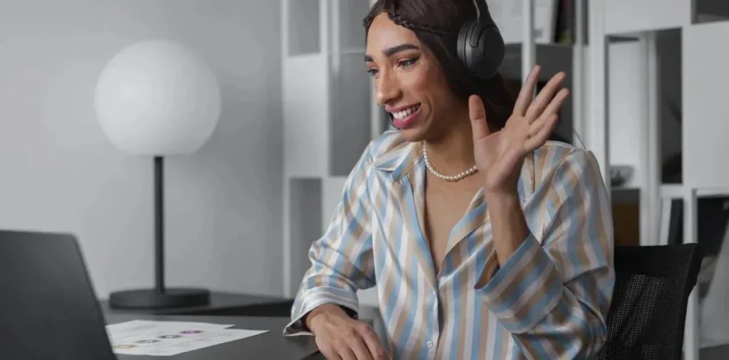 Pós-graduação ideal: como fazer a escolha certa? | Foto de mulher sorrindo usando fones de ouvidos enquanto faz uma reunião no notebook | FAVENI