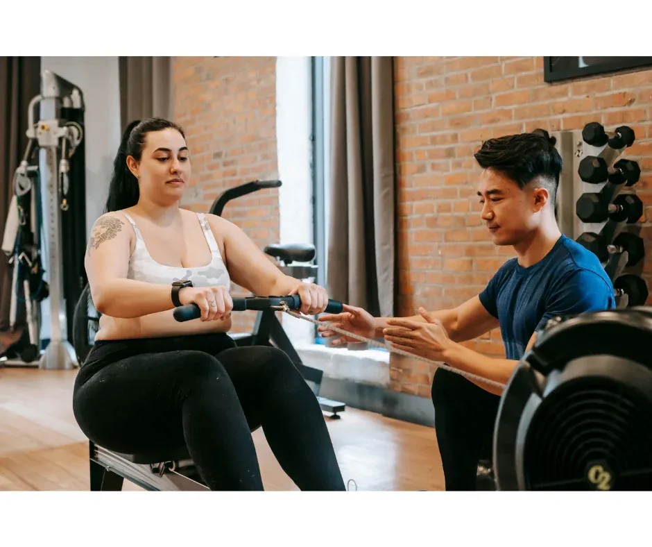 Educação Física na promoção da saúde: qual é a importância? | Foto de personal trainer ajudando aluna a treinar na academia | FAVENI|Educação Física na promoção da saúde: qual é a importância? | Foto de professora de educação física com alunos na quadra | FAVENI