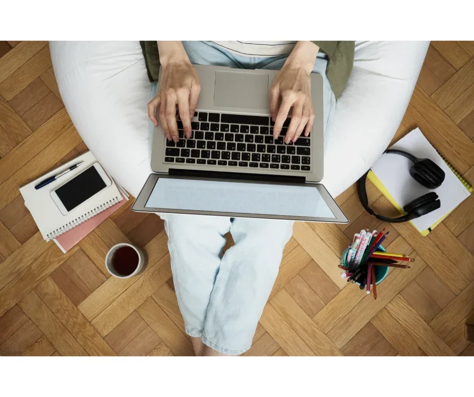 Equipamentos para pós-graduação EaD: o que é preciso? | Foto superior de uma pessoa com notebook no colo digitando algo | FAVENI|Equipamentos para pós-graduação EaD: o que é preciso? | Mulher de fone de ouvido em frente ao notebook | FAVENI